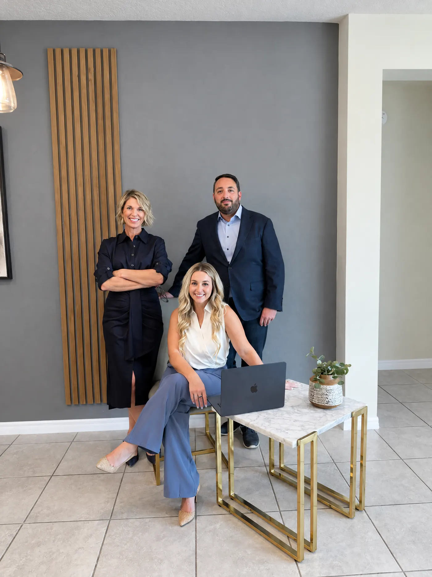 Three Tomegan Marketing Group team members gathered around a laptop