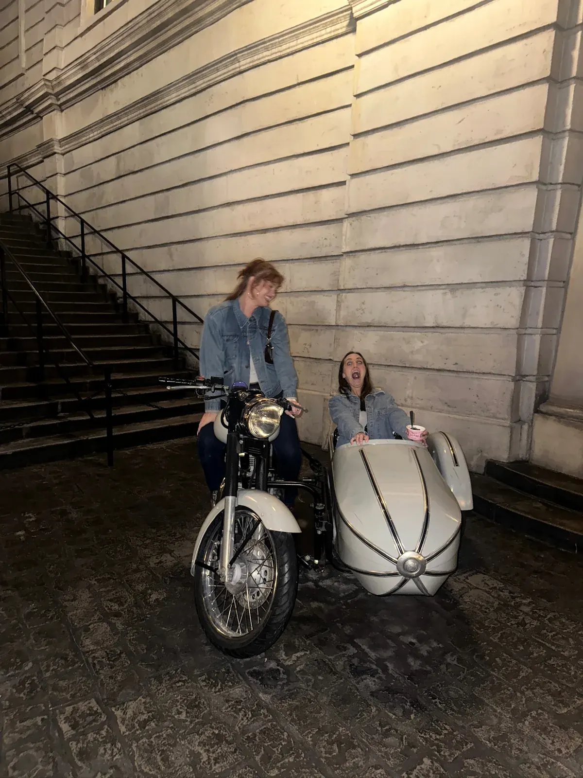 Two Tomegan team members sharing a playful moment on a motorcycle and sidecar