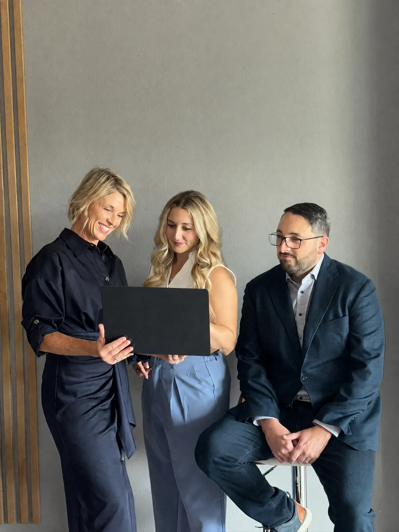 Three Tomegan team members collaborating around a laptop